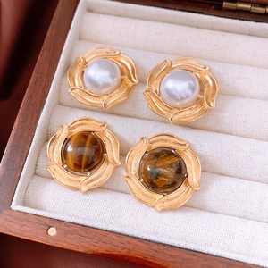 Close-up of vintage gold petal earrings with white pearl and brown tiger eye stone