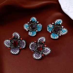 Gros plan de boucles d'oreilles fleurs vintage avec zircons sur satin de soie brun