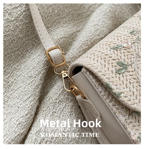 Detail of golden metal lobster clasp and adjustable buckle on woven crossbody saddle bag