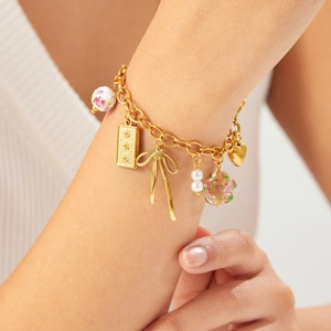 Bracelet doré pastel orné de perles en céramique florales et de breloques nœuds