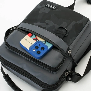 Macro detail of men's crossbody bag featuring waterproof camo fabric and functional zip pocket