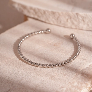 Macro shot of silver twisted cable cuff bracelet with spherical ends on stone base