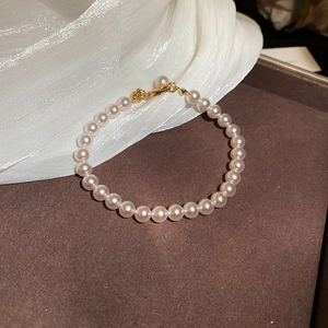 Vue macro de perles roses lustrées avec fermoir plaqué or sur fond en soie blanche