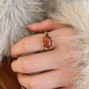 Close-up of gold plated oval red agate ring with beaded edge on a model's finger
