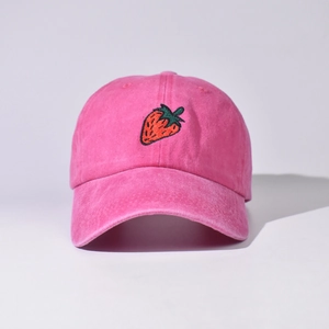 Dettaglio frontale di un cappello da baseball in cotone rosa con ricamo di fragola