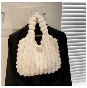 Detail of white plush tote bag with vertical stripes hanging on a black blazer jacket