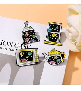 Close-up of enamel pins set featuring starry sky motifs on tv and teapot shapes