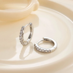Silver hoop earrings with sparkling white zircons displayed on a ceramic tray
