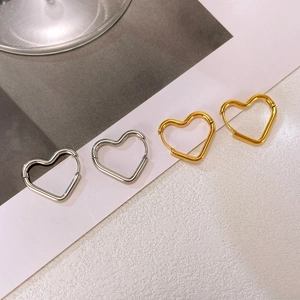 Detail of minimalist gold and silver heart-shaped hoop earrings in polished finish