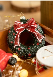 Detailed close-up of a resin Christmas wreath ornament with a red bow and gold string