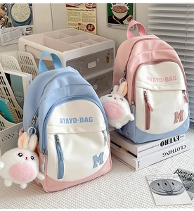 Detail of multi-color nylon school backpack with cute rabbit pendant on a desk