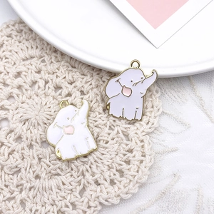 Detailed macro view of two cute white elephant alloy pendants on a beige woven mat background