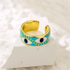 Macro shot of 18K gold plated evil eye ring with blue enamel on a white stone background