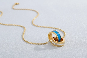 Macro shot of interlocking double ring necklace in gold with blue enamel and rhinestones