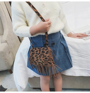 Girl wearing a leopard print crossbody bag with tassels shown from a side profile view