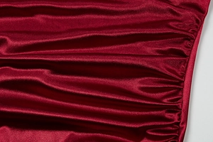 Close-up of wine red satin fabric with elegant ruched details and glossy finish