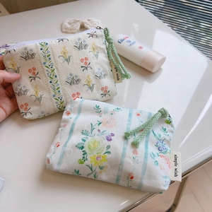 Detail of floral cotton mini bags with zipper and woven cord in a lifestyle setting
