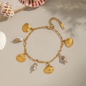 Collier style marin en acier doré avec pendentifs coquillages et conques sur fond beige