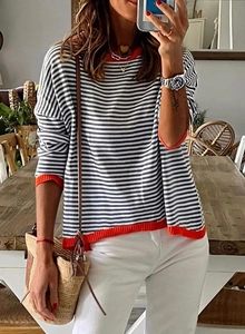 Détail du pull en maille avec rayures noires et blanches et bords contrastés orange