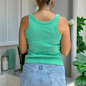 Detail view of the ribbed knit green tank top back texture paired with blue denim jeans