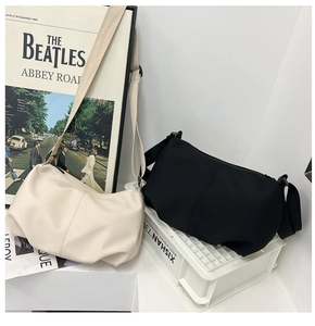 Detail of minimalist oversized crossbody dumpling bags showing soft folds and matte texture