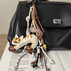 Dettaglio di un ciondolo per borsa a forma di gatto con perline su borsa in pelle