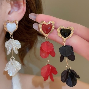 Macro shot of silver needle heart earrings with acrylic petals in white, red and black
