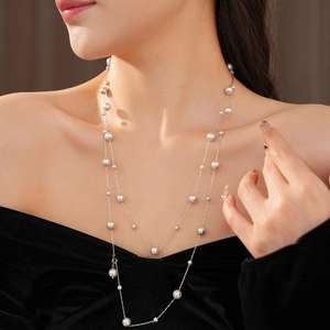 Close-up of double-layered pearl necklace on model's neck with silver chain and white beads