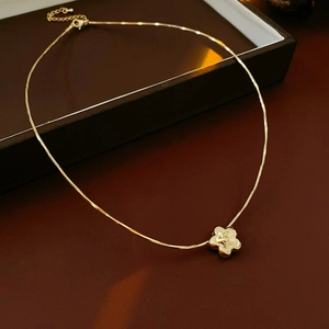Dettaglio di una collana con ciondolo a fiore dorato e chiusura a moschettone regolabile