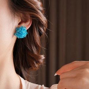 Macro shot of blue glass seed bead cluster earrings worn on model's ear