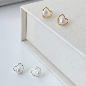 Detail of hollow heart stud earrings with freshwater pearls in gold and silver finish