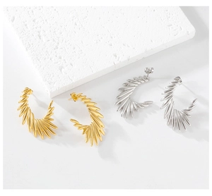 Detail of C-shaped wing earrings in gold and silver with radial spiral texture