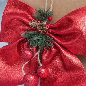 Red glitter Christmas bow with pine cones and green needles for tree decoration