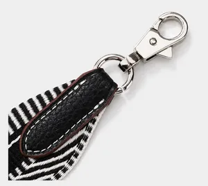 Details von silbernem Karabiner mit schwarzem Leder und monochromem Webriemen