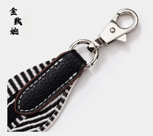 Detail of silver snap hook with black litchi leather and monochrome chevron strap