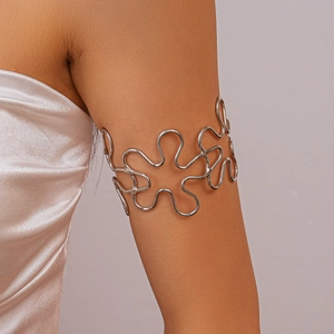 Macro detail of polished silver metal arm cuff with fluid wave design on upper arm