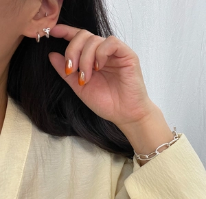 Detail of 925 sterling silver bow earrings and thick chain bracelet on model
