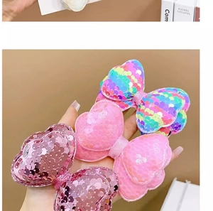Detailed view of handmade bow hair clips with glitter sequins in pink and rainbow colors