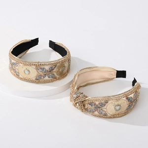 Lace embroidered headband with sequins and colorful floral patterns on white stand