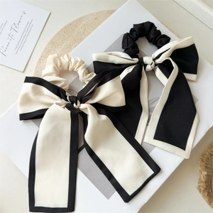 Detail of elegant black and white oversized bow scrunchies with long ribbons on a magazine