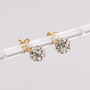 Close-up of golden spherical stud earrings with sparkling pavé crystals on a clear stand