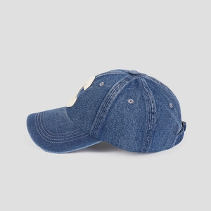 Detail of navy blue denim baseball cap featuring white applique patch and grey eyelets