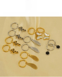 Detail of 18K vacuum plated earrings with cross, butterfly, and wing charms on satin