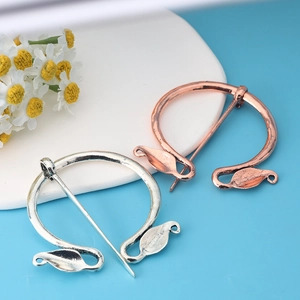 Detailed view of vintage silver and rose gold Viking brooches with leaf design elements