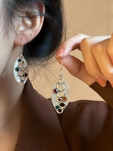 Détail de boucles d'oreilles feuille argentée avec texture et pierres précieuses