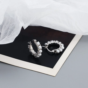 Detailed view of silver hoop earrings with white pearls featuring the S925 hallmark