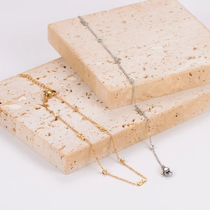 Gold and silver minimalist LOVE anklets with sparkling crystals on stone pedestals