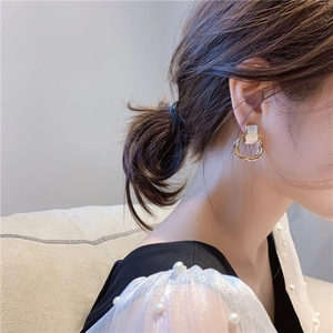 Detailed view of vintage gold hoop earrings with white cat eye stone on a female model