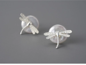 Macro shot of S925 silver dragonfly earrings featuring brushed texture and white pearls