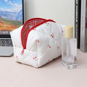 Quilted floral cosmetic bag featuring cherry patterns and a red checkered lining detail